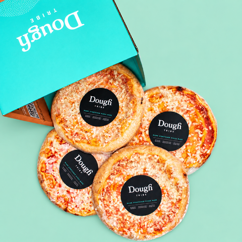 Four round pizza slices with black circular Dough Tribe labels are arranged on a mint green background next to an open turquoise box with the Dough Tribe logo.