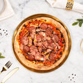 Cooked Doughvinci Meatlovers pizza topped with salami, ham, tomato sauce and melted cheese on a blistered woodfired sourdough crust, served on a gold tray on white marble with gold cutlery and a linen napkin