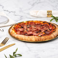 Cooked Doughvinci Meatlovers pizza topped with salami, ham, tomato sauce and melted cheese on a blistered woodfired sourdough crust, served on a gold tray on white marble with gold cutlery and a linen napkin